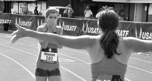 Becky Bowman, with a 14.15 windy 100, gets all-arms reception from W50 runner-up Amanda Scotti.
