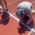 Jeff Davison secures tape marking start of 80-meter hurdles for certain men's and women's age groups.